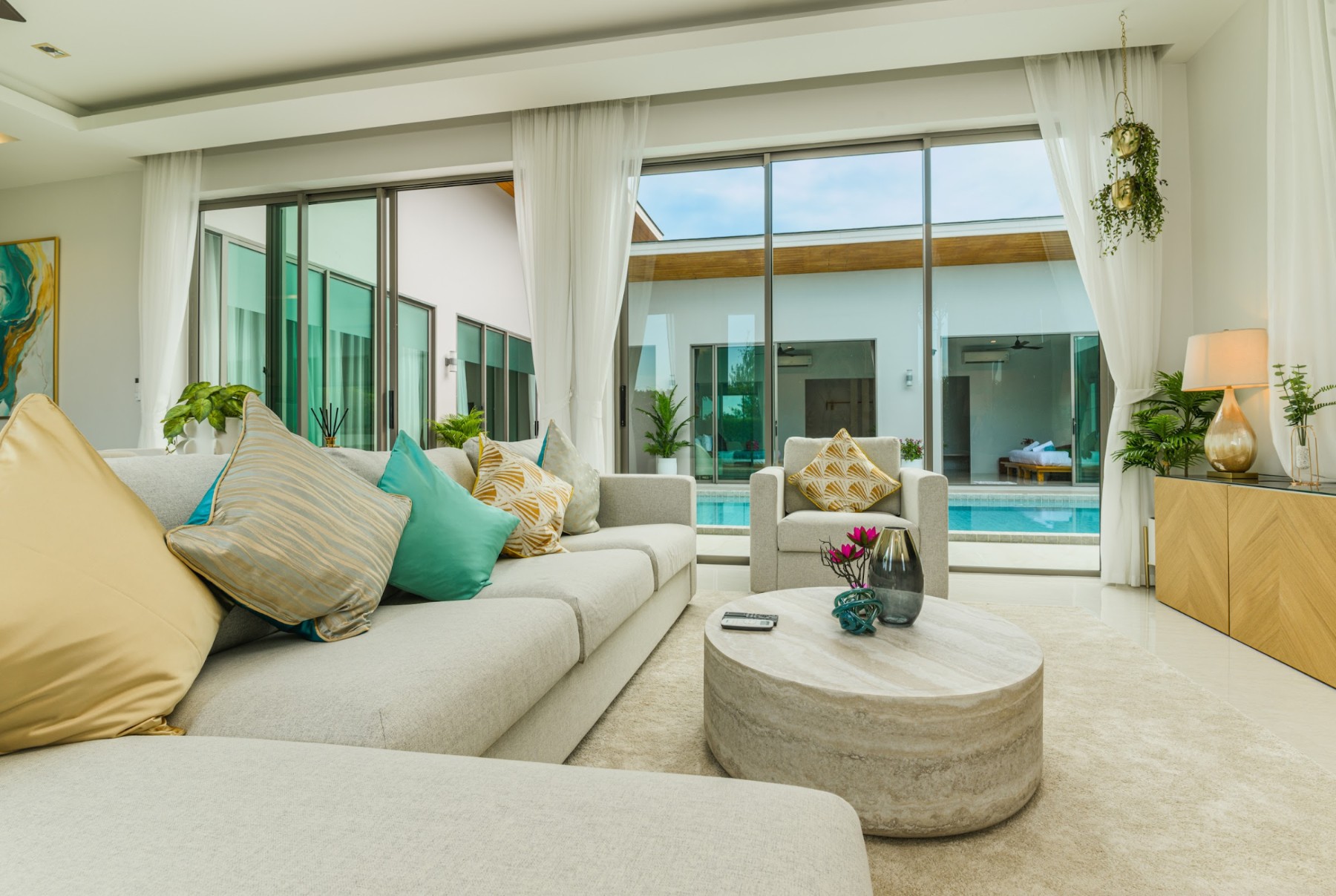 An open plan villa living room in Phuket opening onto the pool terrace